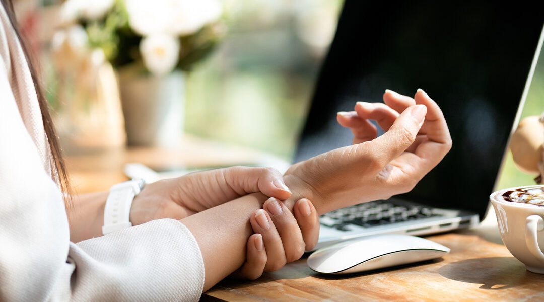 person holding wrist at desk