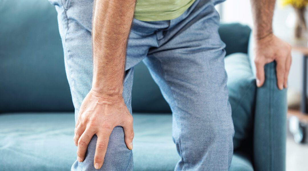 person holding knee as the get off of couch