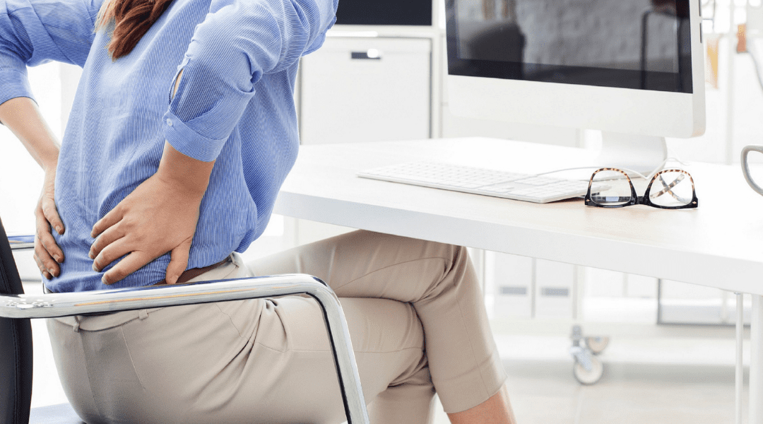 woman holding back at desk