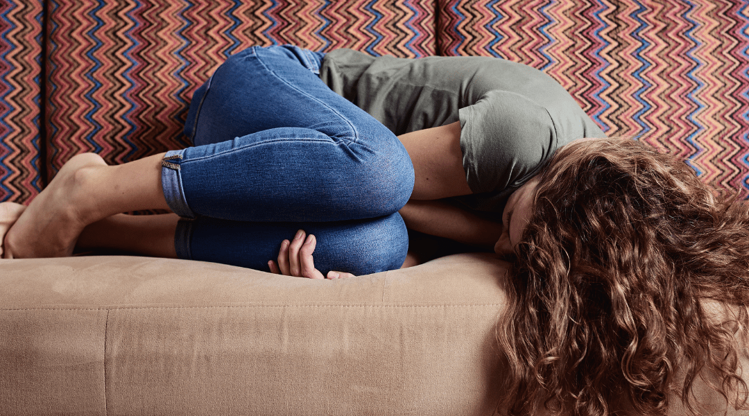 woman curled up on couch from chronic depression