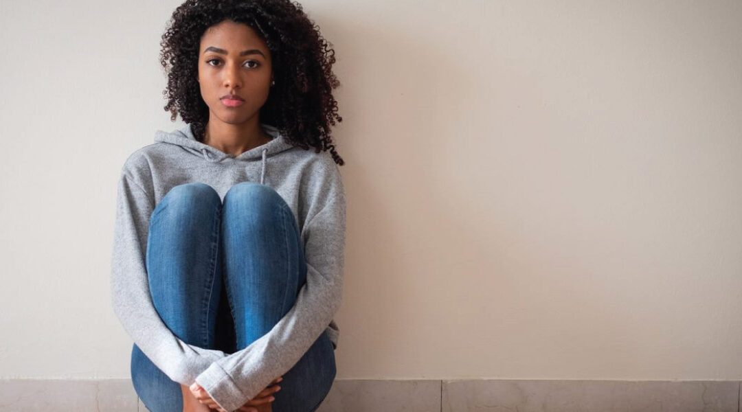 sad woman sitting against wall